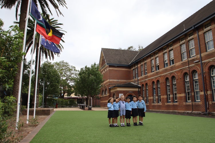 students outside near the flagpoles at drummoyne public school